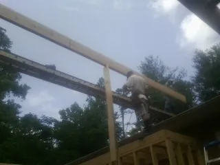 Carpenter setting a ridge beam over a new addition frame — Ice Dam Removal by Roofing Brothers in Hill City